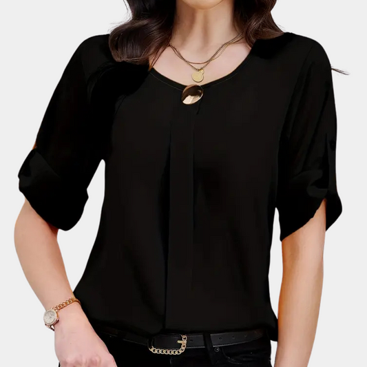 Frau in schwarzer Bluse mit kurzen Ärmeln, goldener Halskette und Armbanduhr.