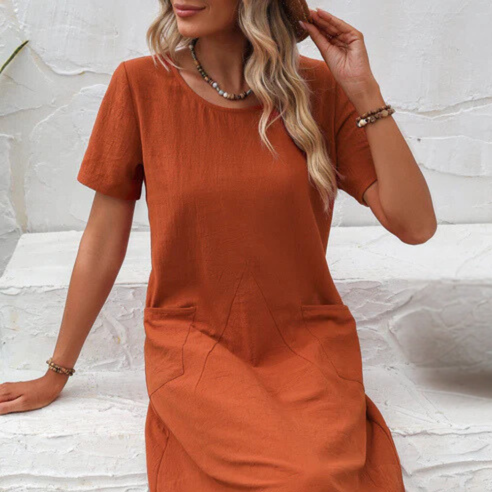 Frau in orangefarbenem Leinenkleid, Sommermode, lässiger Stil, Accessoires, weiße Wand.