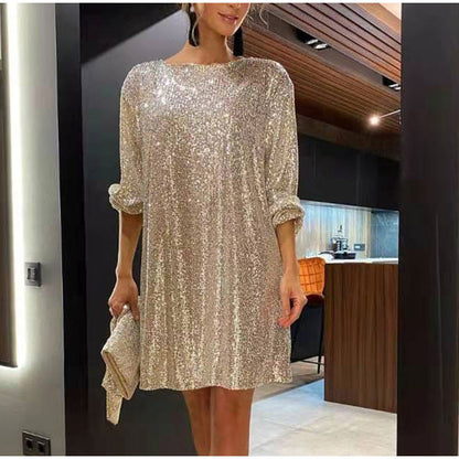 Frau in glitzerndem, goldenen Paillettenkleid, elegantes Abendoutfit, moderne Innenarchitektur.