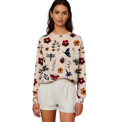 Frau in cremefarbenem Pullover mit Blumenmuster und weißen Shorts, modisch, elegant.