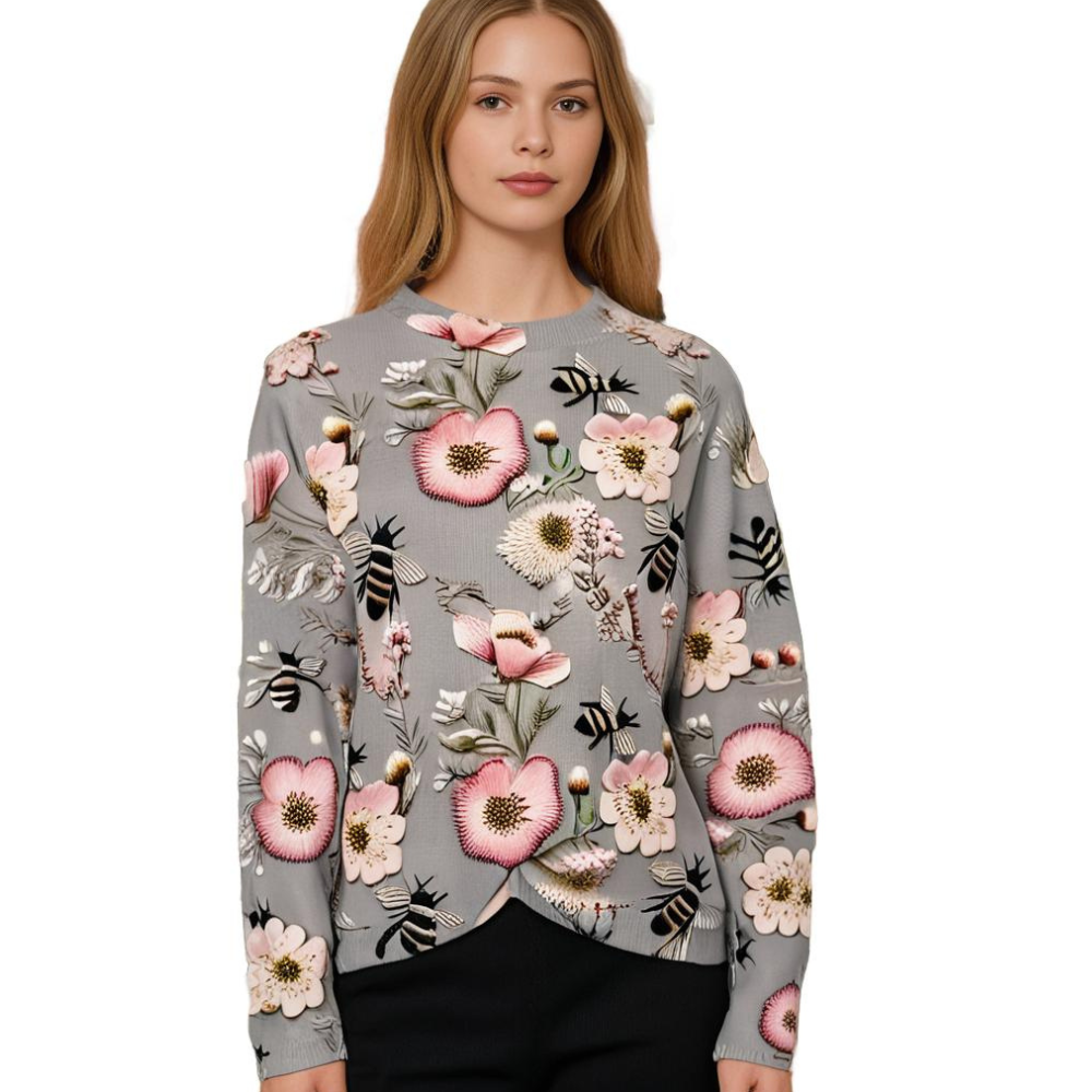 Frau in grauem Pullover mit Blumenmuster, rosa Akzenten, Bienenmotiv, modisch, elegant.