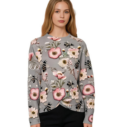 Frau in grauem Pullover mit Blumenmuster, rosa Akzenten, Bienenmotiv, modisch, elegant.