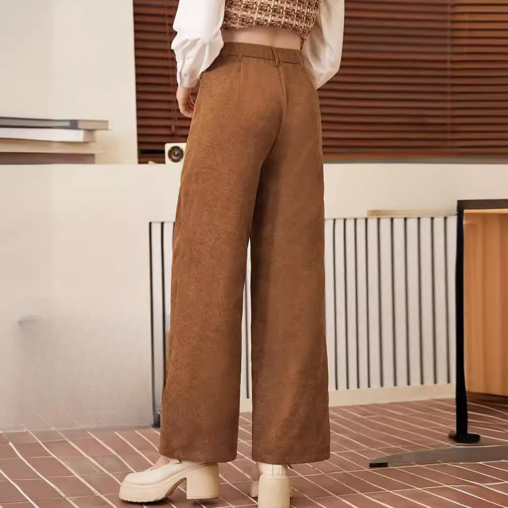Frau in brauner Cordhose, weites Bein, modisch, Herbstmode, Innenraum, Rückansicht.