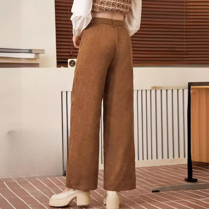 Frau in brauner Cordhose, weites Bein, modisch, Herbstmode, Innenraum, Rückansicht.