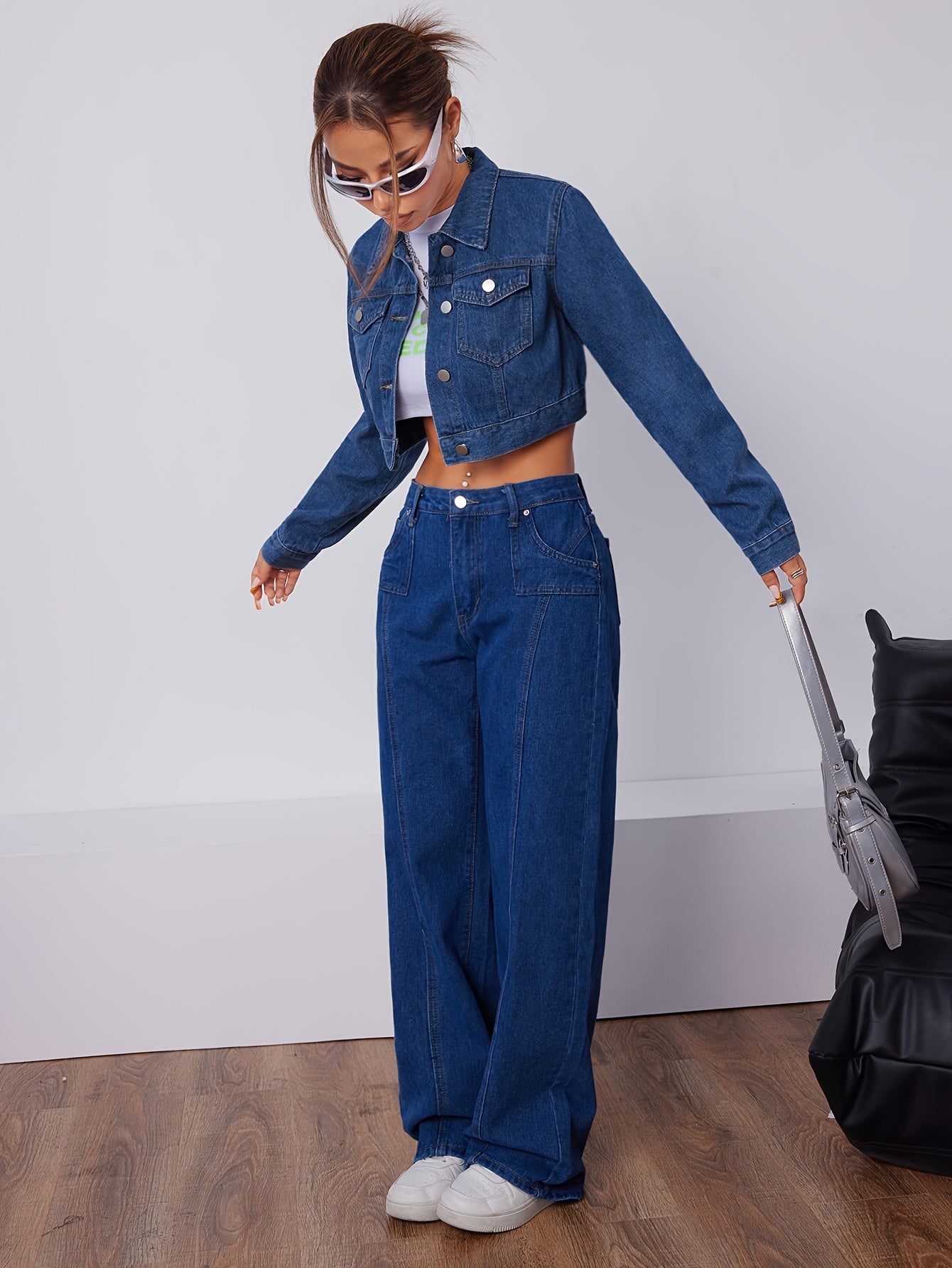 Frau in blauer Jeansjacke und Jeanshose, weiße Sneakers, modisch, lässiger Stil, Holzfußboden.