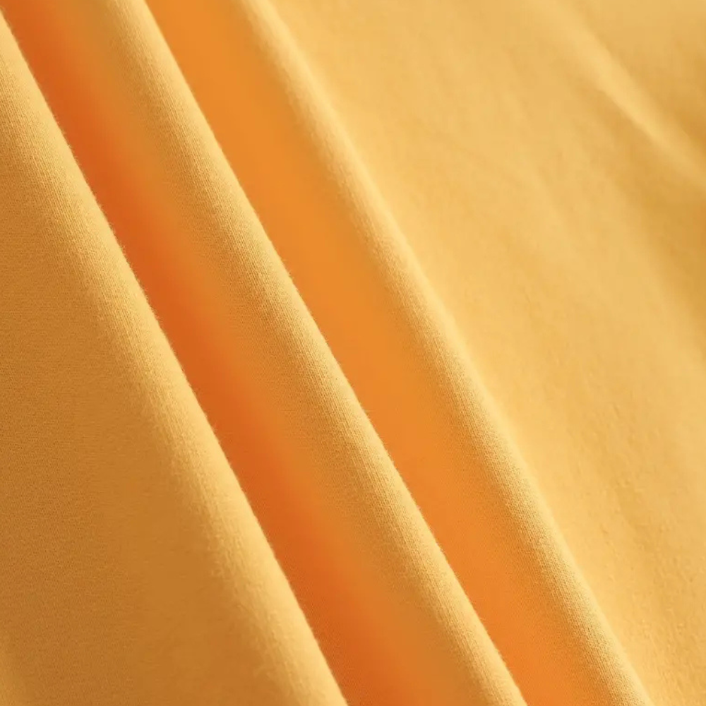 Gelber Baumwollstoff, Nahaufnahme, weiche Textur, ideal für Kleidung und Heimtextilien.