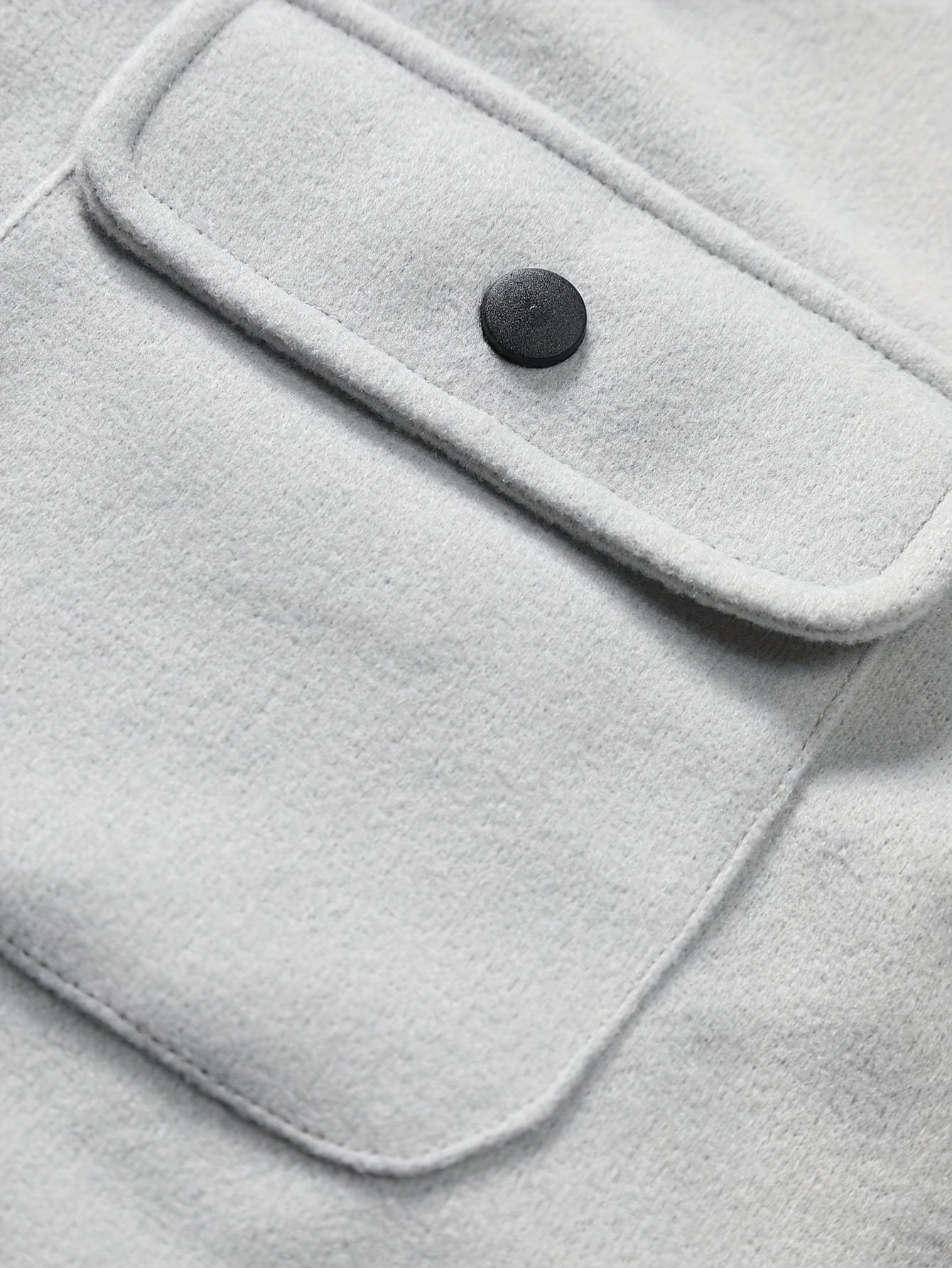 Graue Wolljacke mit schwarzem Knopf und Brusttasche, stilvoll und warm, ideal für Herbstmode.