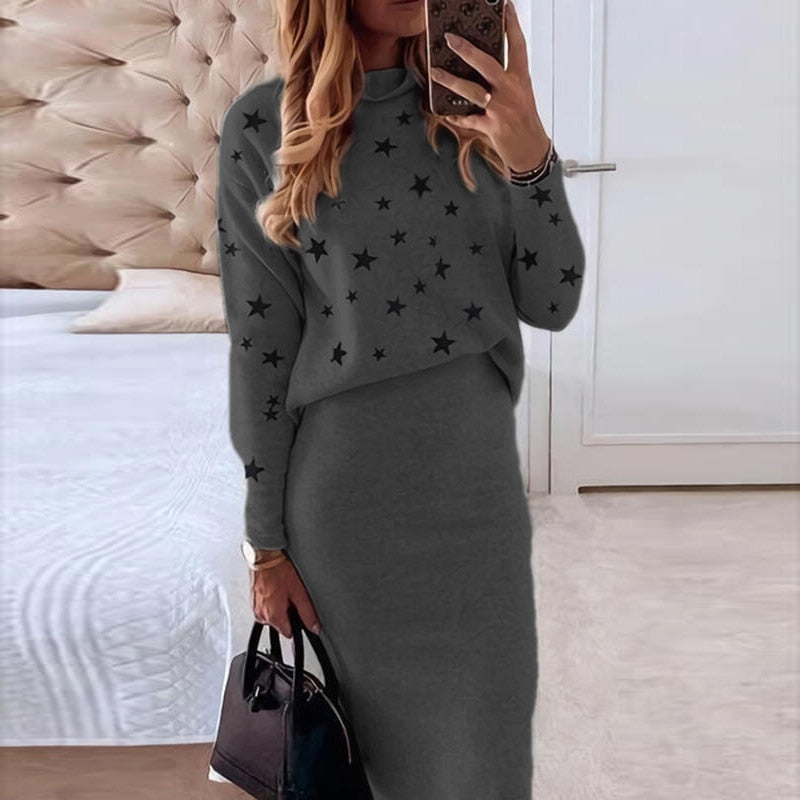 Frau in grauem Strickkleid mit Sternenmuster, hält schwarze Handtasche, modernes Schlafzimmer.