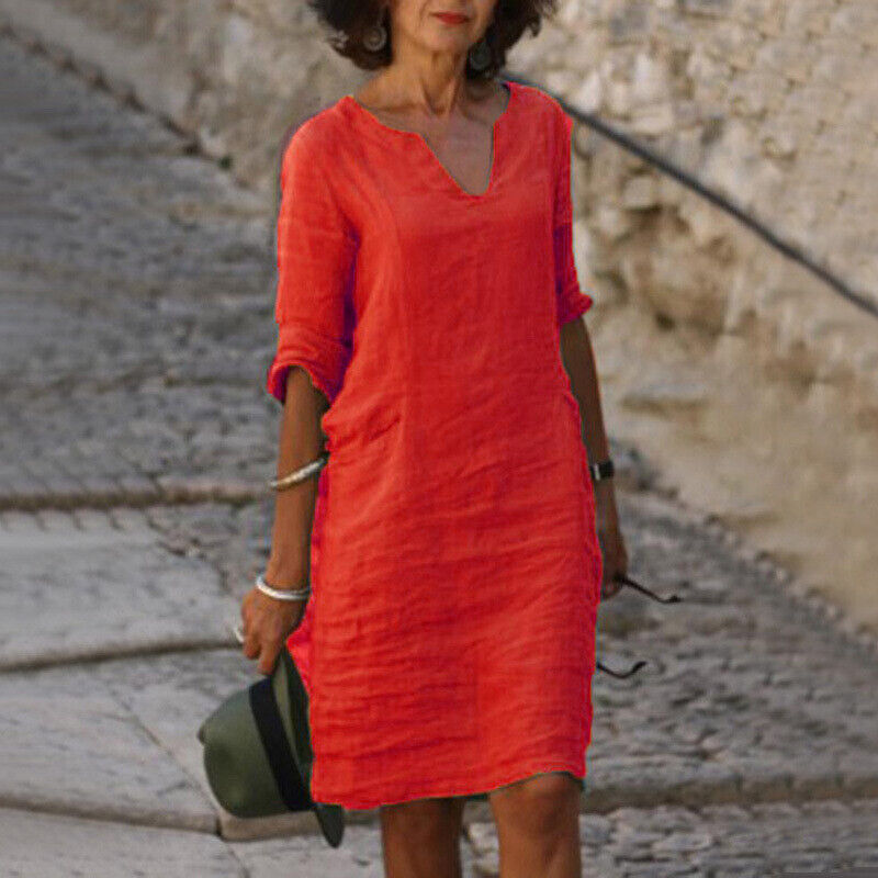 Frau in rotem Leinenkleid, Sommermode, lässig, V-Ausschnitt, Spaziergang auf Kopfsteinpflaster.